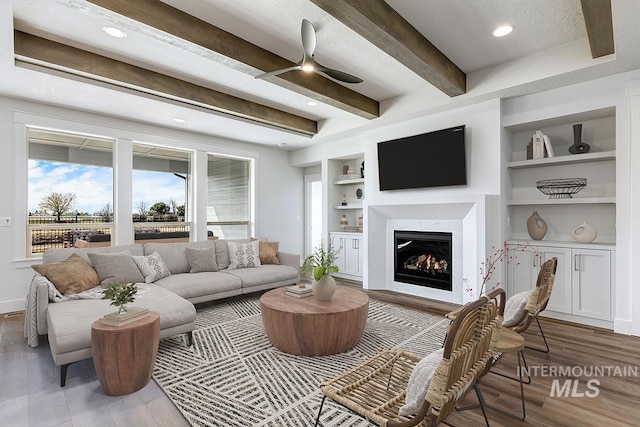 7029 S Tindaris Ave, Meridian, ID 83642 - living room featuring a high end fireplace, beamed ceiling, built in shelves, wood finished floors, and ceiling fan