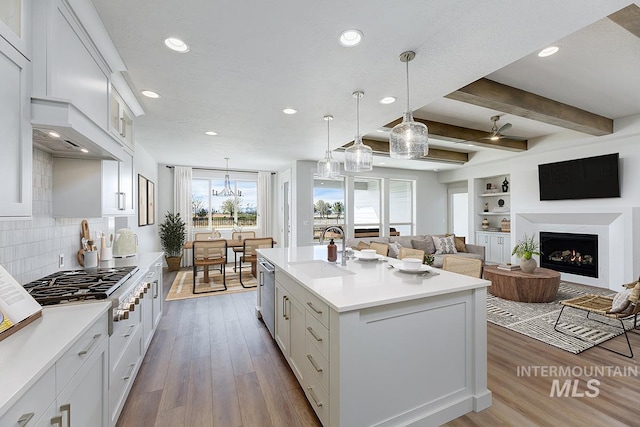 7029 S Tindaris Ave, Meridian, ID 83642 - kitchen with stainless steel appliances, light countertops, wood finished floors, white cabinetry, and beam ceiling