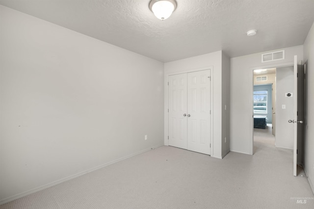 unfurnished bedroom featuring visible vents, light carpet, baseboards, and a closet