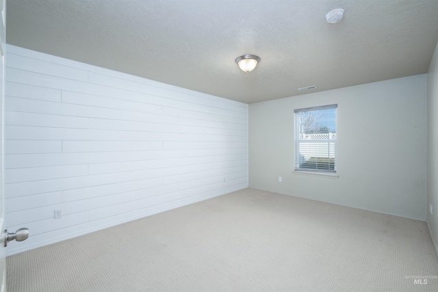 carpeted spare room featuring a textured ceiling and visible vents