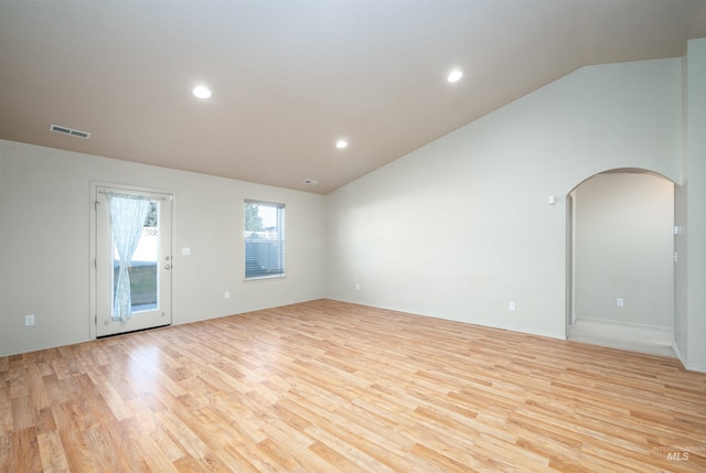 spare room featuring light wood-style flooring, arched walkways, vaulted ceiling, visible vents, and recessed lighting