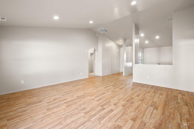 unfurnished room with recessed lighting, arched walkways, lofted ceiling, and light wood-type flooring