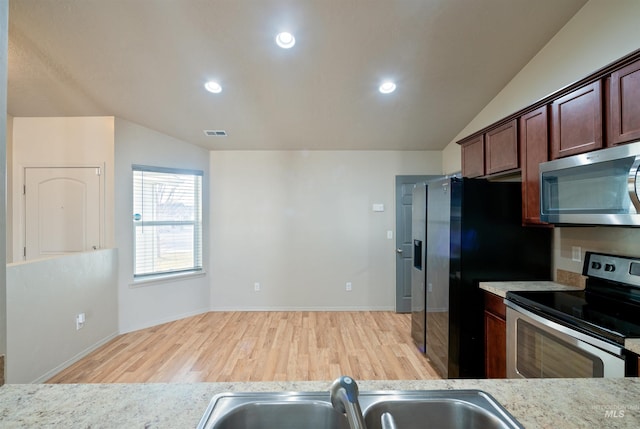kitchen featuring lofted ceiling, wood finished floors, a sink, and appliances with stainless steel finishes