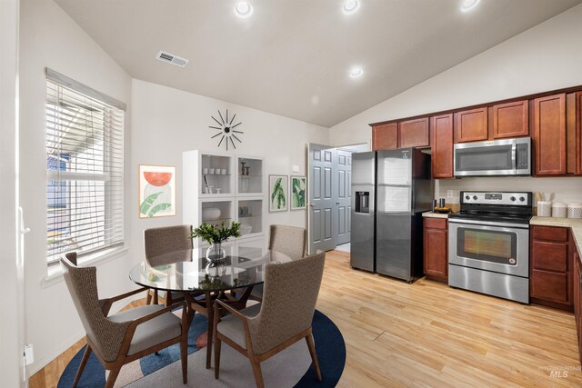 kitchen with light wood finished floors, lofted ceiling, visible vents, and appliances with stainless steel finishes