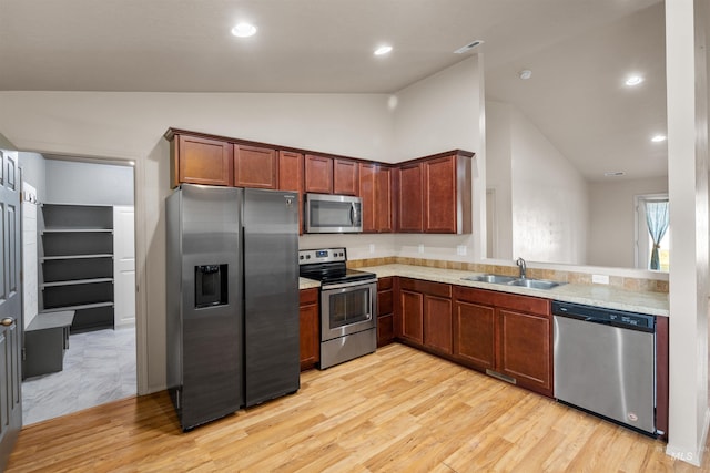 kitchen featuring light countertops, light wood-style flooring, stainless steel appliances, and a sink