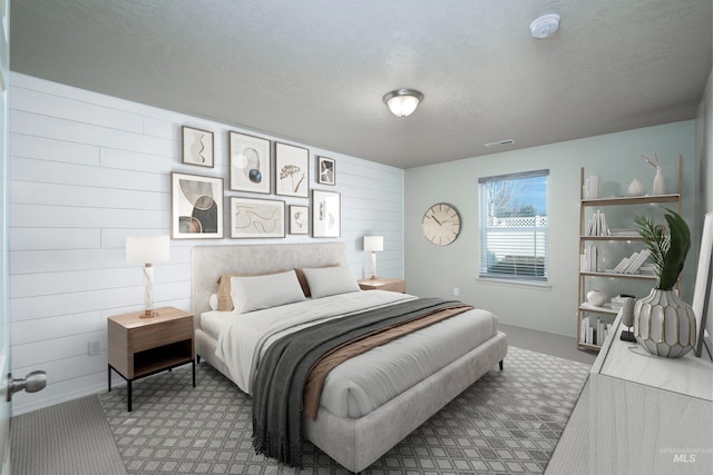 bedroom with carpet floors, visible vents, wood walls, and baseboards