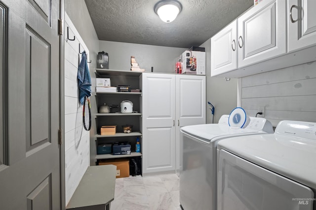 washroom with separate washer and dryer, marble finish floor, a textured ceiling, and cabinet space