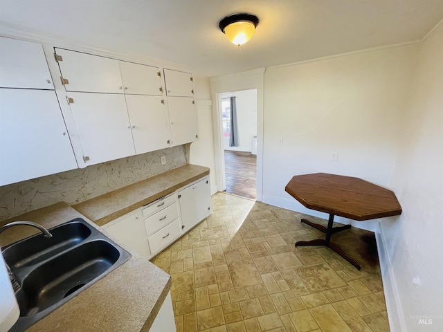 kitchen with tasteful backsplash, white cabinetry, and sink