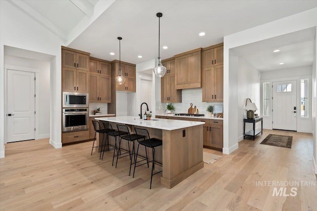 kitchen featuring brown cabinetry, stainless steel appliances, light wood-type flooring, and a sink