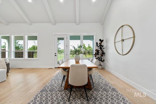 dining room featuring vaulted ceiling with beams, light wood-style floors, and baseboards