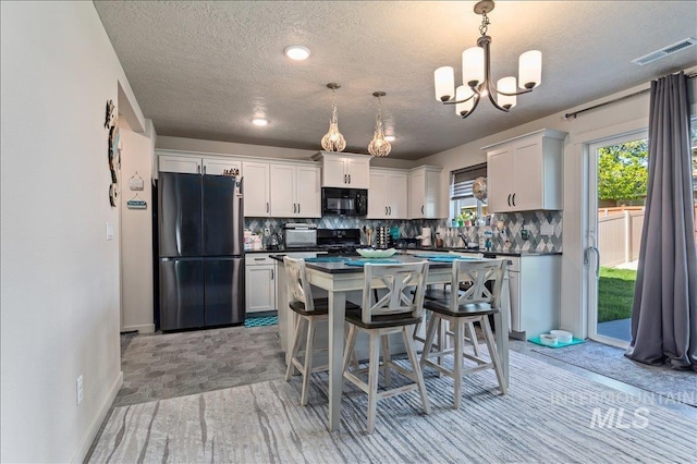 kitchen featuring dark countertops, a kitchen island, black appliances, white cabinetry, and backsplash