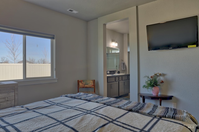 bedroom featuring ensuite bath, visible vents, and a sink