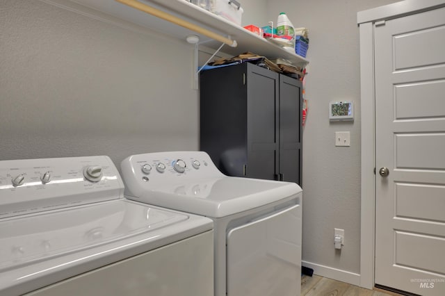 laundry room with cabinet space, baseboards, a textured wall, washer and dryer, and light wood-style floors