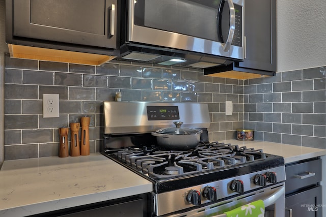 kitchen featuring light stone counters, stainless steel appliances, and backsplash