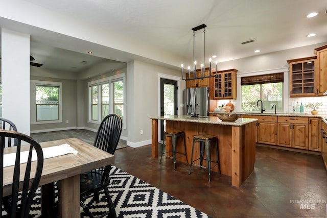570 E Ocelot, Meridian, ID 83646 - kitchen with stainless steel refrigerator with ice dispenser, a center island, light stone countertops, a sink, and a kitchen bar