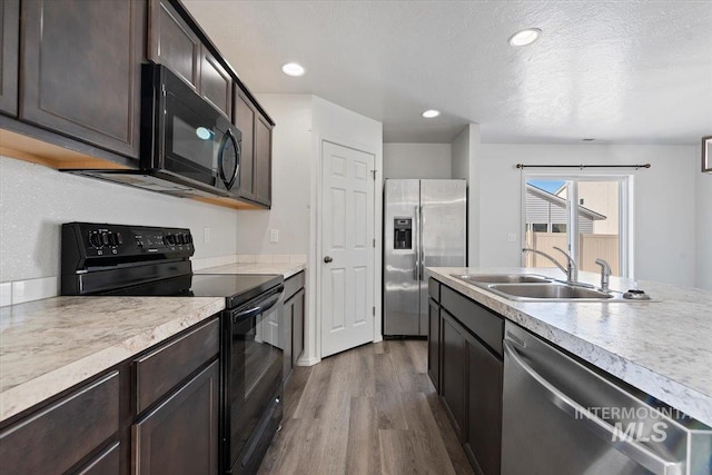 kitchen with sink, dark hardwood / wood-style flooring, dark brown cabinetry, black appliances, and a textured ceiling