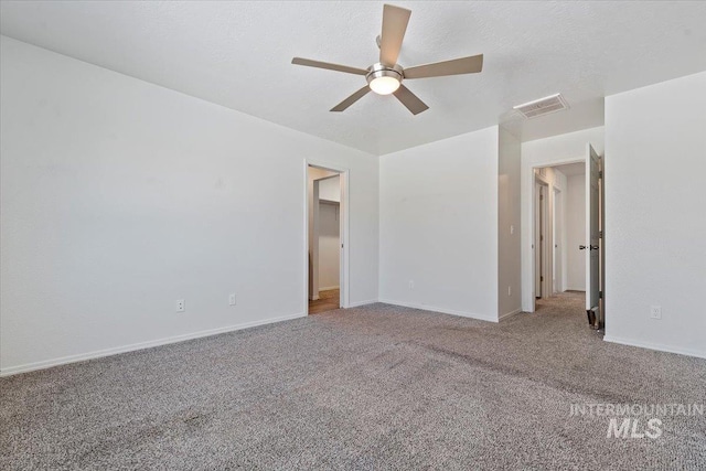 empty room with ceiling fan, carpet floors, and a textured ceiling