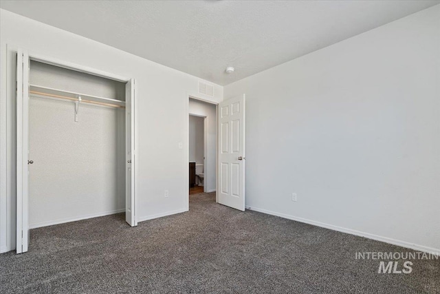 unfurnished bedroom with dark carpet, a closet, and a textured ceiling