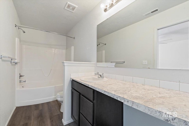 full bathroom featuring shower / tub combination, wood-type flooring, vanity, toilet, and a textured ceiling