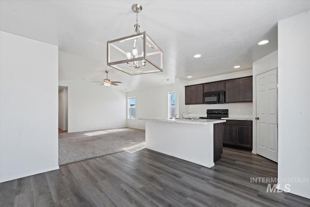 kitchen with dark hardwood / wood-style floors, hanging light fixtures, dark brown cabinetry, black appliances, and a center island with sink