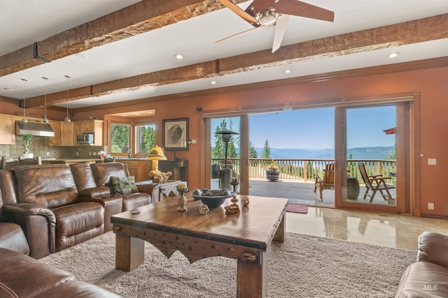 living area featuring ceiling fan, beamed ceiling, recessed lighting, a mountain view, and baseboards