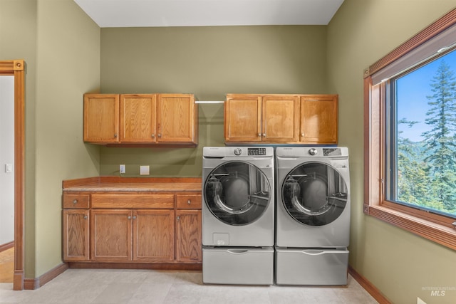 laundry area with cabinet space, washer and clothes dryer, healthy amount of natural light, and baseboards