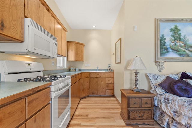 kitchen with white appliances, a sink, light wood-style floors, recessed lighting, and light countertops