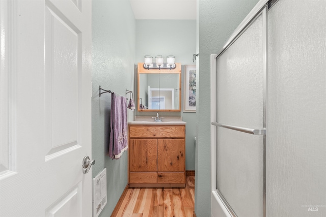 full bath with wood finished floors, a shower stall, and vanity
