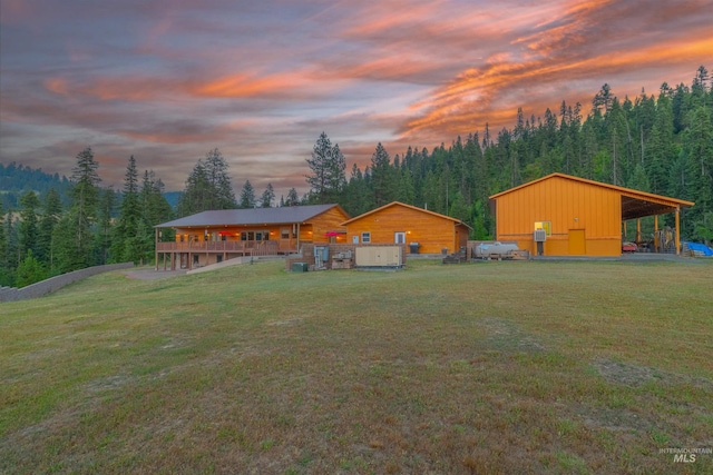 back of property at dusk with a lawn, a view of trees, and board and batten siding