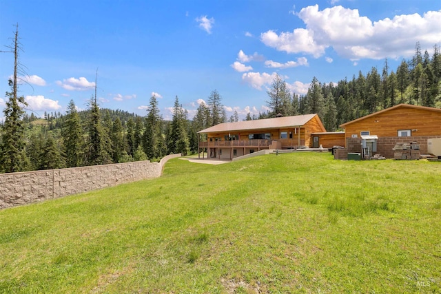 view of grassy yard featuring a wooded view and a deck