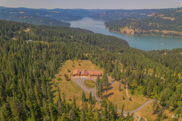 drone / aerial view of a heavily wooded area and a water and mountain view