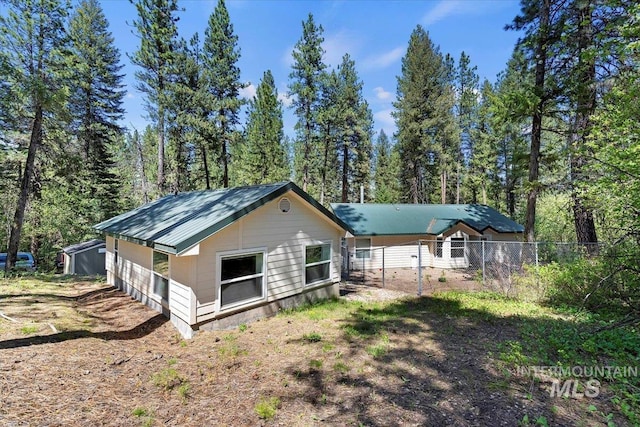 104 Sky Ridge Dr, Garden Valley, ID 83622 - back of property featuring fence, metal roof, and a wooded view