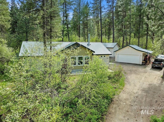 104 Sky Ridge Dr, Garden Valley, ID 83622 - view of front facade featuring an outdoor structure, metal roof, a garage, and a forest view