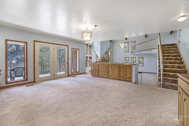 569 Spring Creek Rd, Burley, ID 83318 - unfurnished living room with stairway, light carpet, a chandelier, a textured ceiling, and french doors