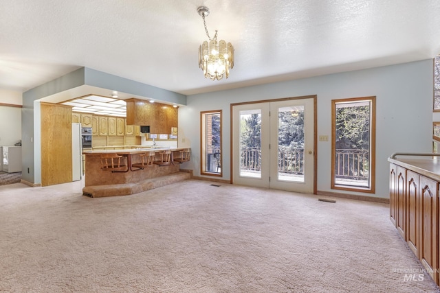 569 Spring Creek Rd, Burley, ID 83318 - living room with a chandelier, light carpet, baseboards, and independent washer and dryer