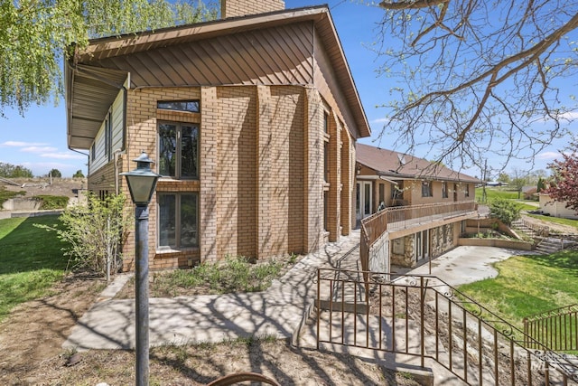 569 Spring Creek Rd, Burley, ID 83318 - view of property exterior featuring a patio area, a chimney, brick siding, stairs, and a lawn