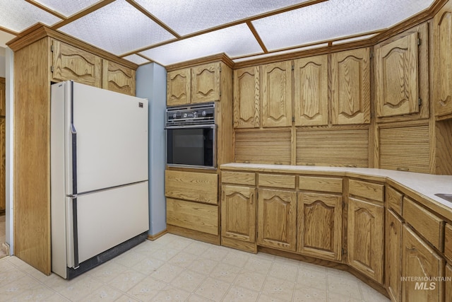 569 Spring Creek Rd, Burley, ID 83318 - kitchen featuring freestanding refrigerator, black oven, brown cabinets, and light countertops