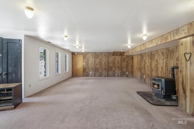 569 Spring Creek Rd, Burley, ID 83318 - unfurnished living room with wooden walls, light carpet, and a wood stove