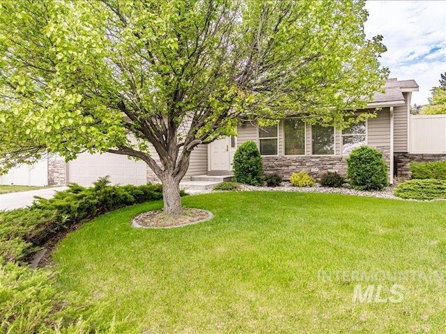 view of property hidden behind natural elements featuring a garage and a front lawn