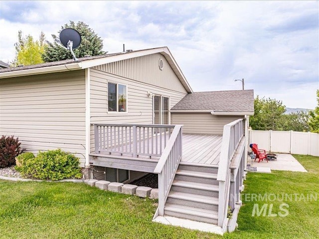 rear view of house with a wooden deck, a patio, and a lawn