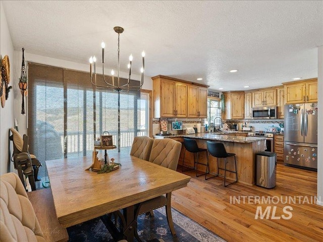 dining space featuring an inviting chandelier, hardwood / wood-style floors, sink, and a textured ceiling