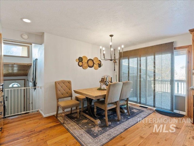 dining area featuring hardwood / wood-style floors, a notable chandelier, and a textured ceiling