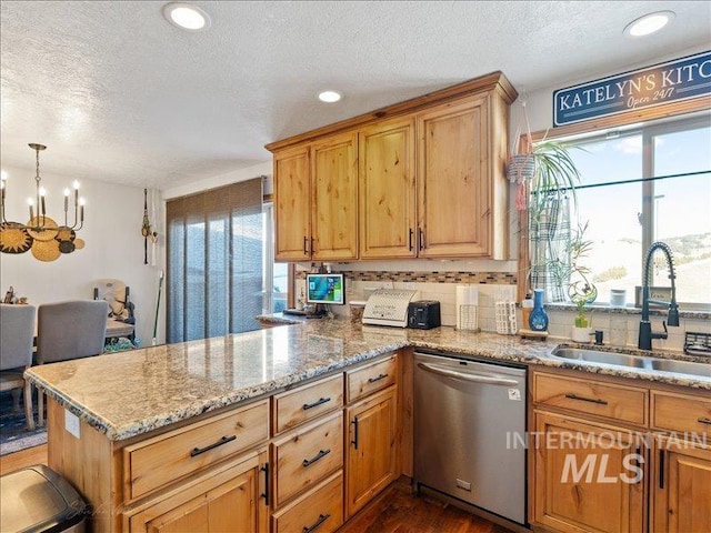 kitchen featuring tasteful backsplash, dishwasher, sink, hanging light fixtures, and kitchen peninsula