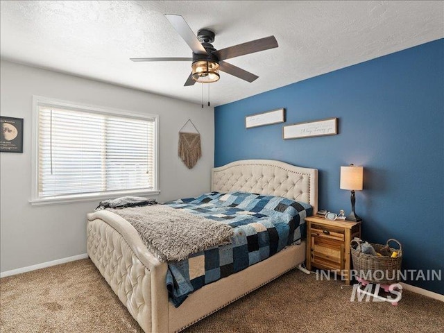 carpeted bedroom featuring ceiling fan and a textured ceiling