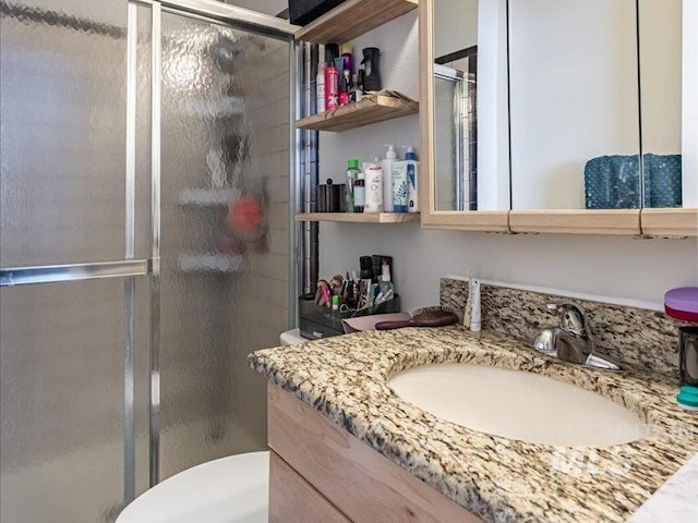 bathroom featuring vanity, toilet, and a shower with shower door