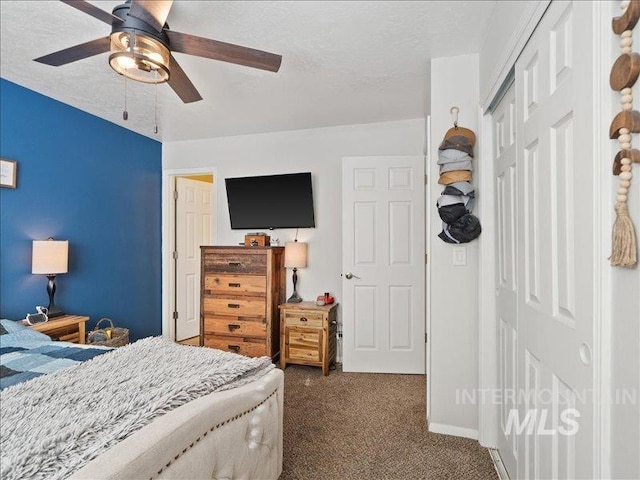 bedroom with ceiling fan, a closet, dark carpet, and a textured ceiling