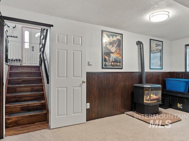 interior space with a healthy amount of sunlight, wooden walls, a textured ceiling, and a wood stove