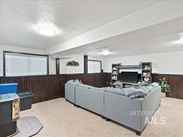 living room featuring light carpet, a textured ceiling, and wood walls