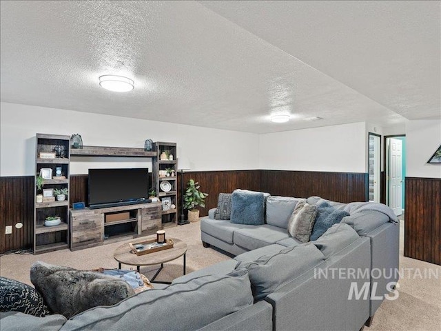 living room with light colored carpet, a textured ceiling, and wood walls