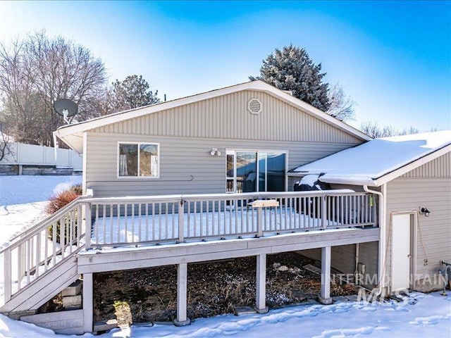 snow covered back of property with a deck